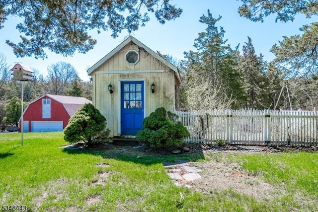 view of barn featuring fence and a lawn