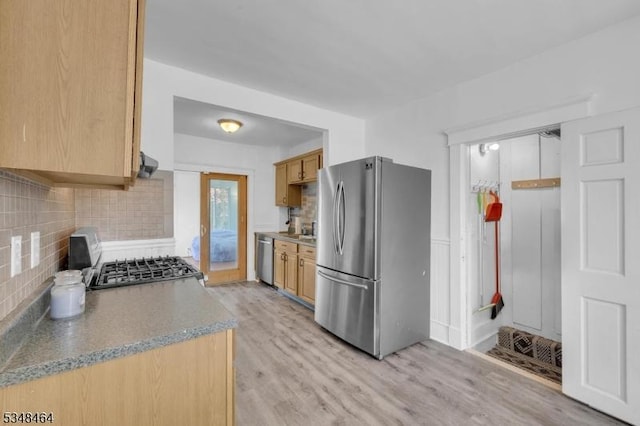 kitchen featuring tasteful backsplash, ventilation hood, stainless steel appliances, and light wood finished floors