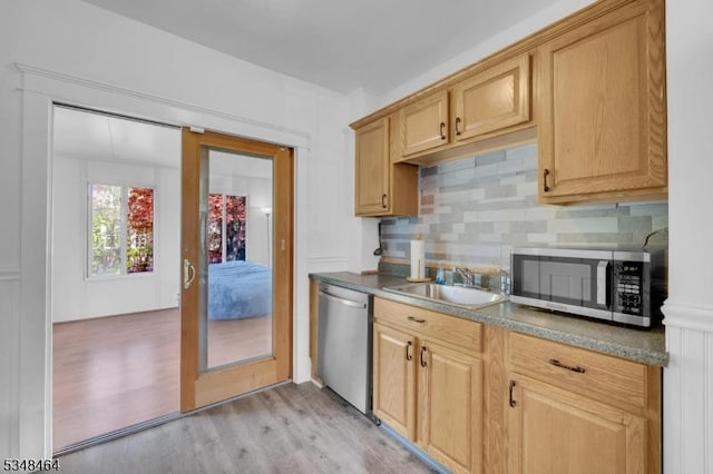 kitchen featuring a sink, light wood-style flooring, appliances with stainless steel finishes, and backsplash