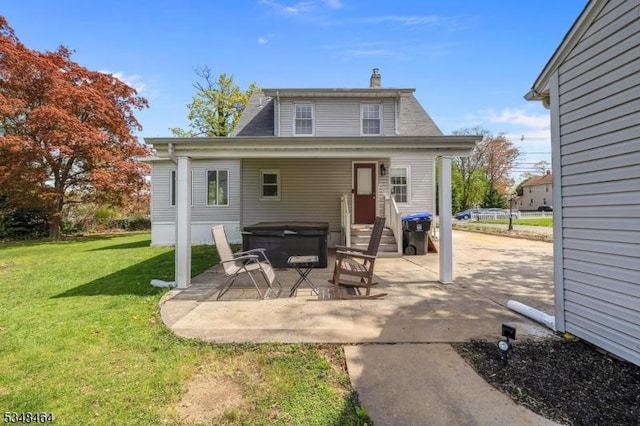 exterior space featuring a patio, a hot tub, a yard, and a chimney
