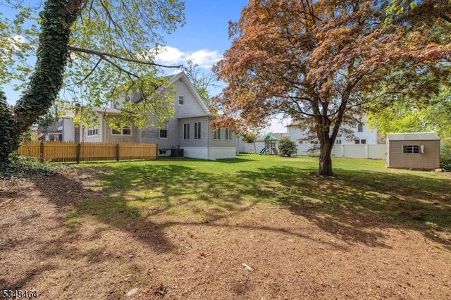 view of yard with fence, an outbuilding, a shed, and a playground