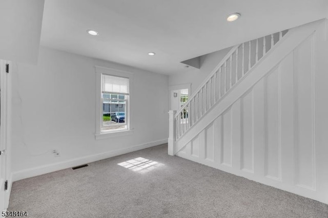 unfurnished living room with stairway, baseboards, carpet, and recessed lighting