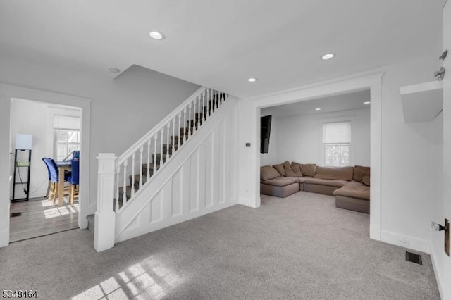 carpeted living area featuring recessed lighting, stairs, a healthy amount of sunlight, and visible vents
