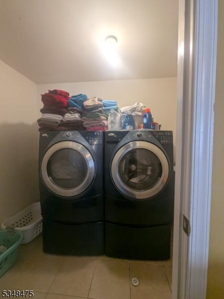 laundry area featuring washing machine and clothes dryer and tile patterned floors