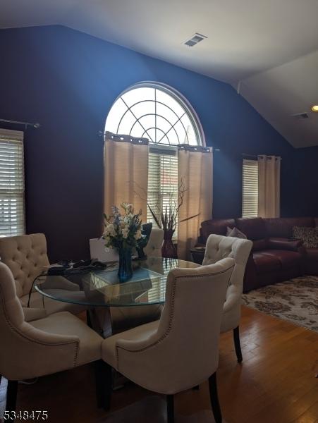 dining space with vaulted ceiling, wood finished floors, and healthy amount of natural light