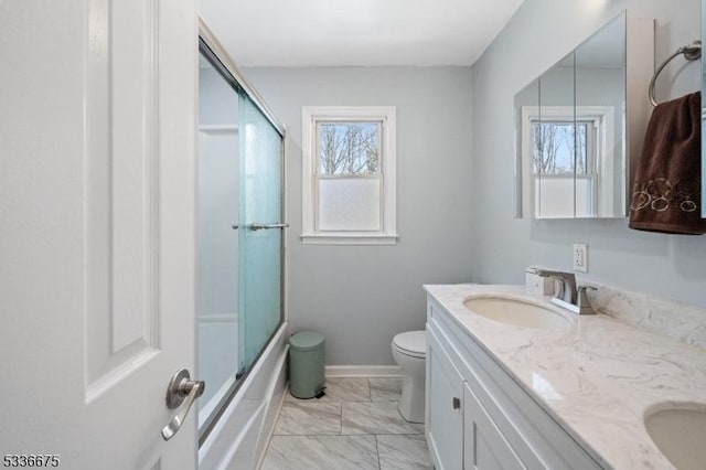full bath with toilet, a sink, marble finish floor, baseboards, and double vanity