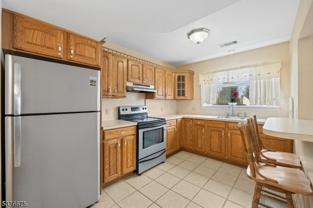 kitchen with light countertops, a sink, appliances with stainless steel finishes, glass insert cabinets, and under cabinet range hood