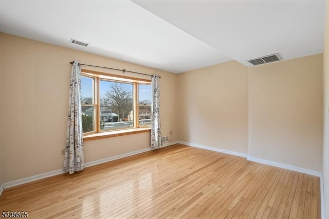 unfurnished room featuring baseboards, visible vents, and hardwood / wood-style floors