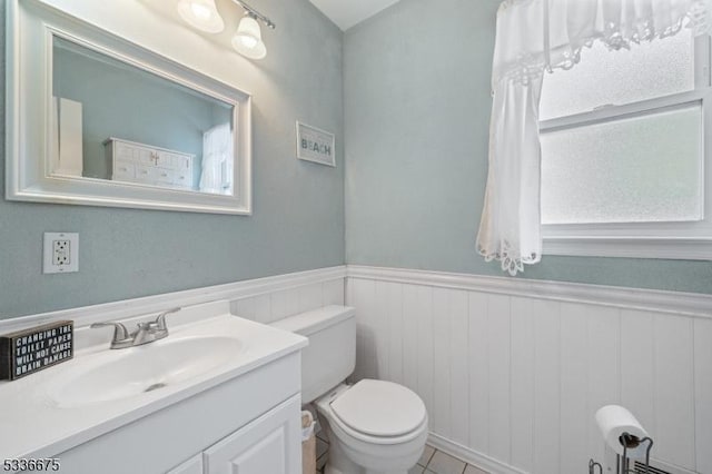 half bathroom with a wainscoted wall, vanity, and toilet