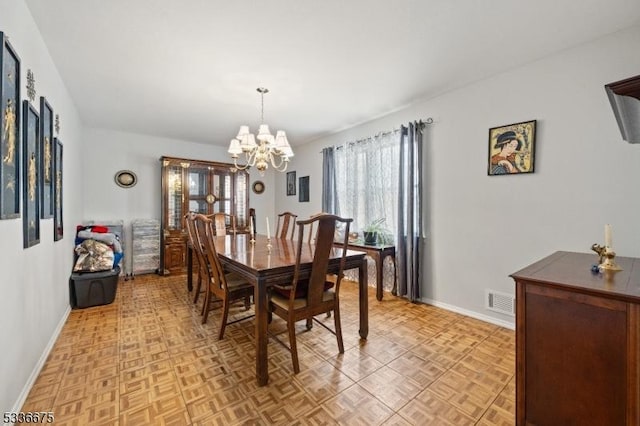 dining room featuring baseboards, visible vents, and a chandelier