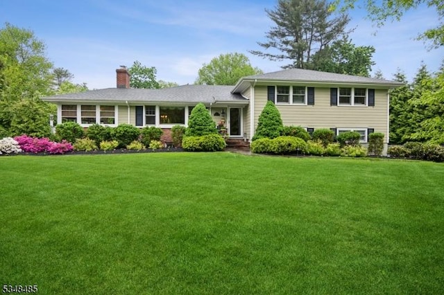 tri-level home featuring a chimney and a front lawn