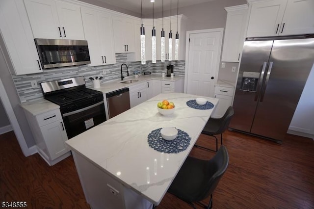 kitchen with a center island, white cabinets, a sink, appliances with stainless steel finishes, and a kitchen breakfast bar
