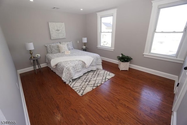 bedroom with wood finished floors, baseboards, and visible vents