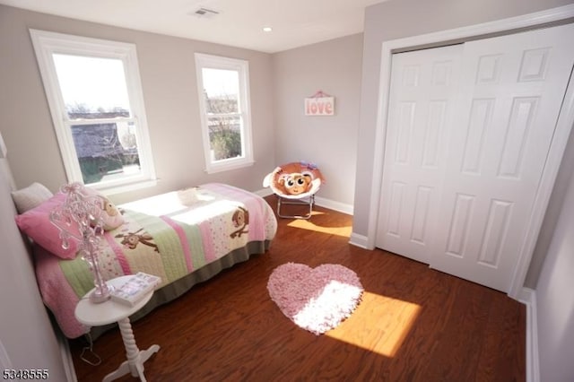 bedroom with visible vents, a closet, baseboards, and dark wood finished floors