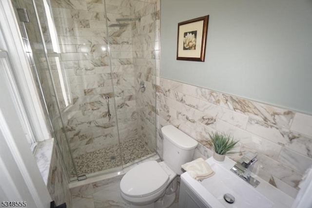 full bath featuring a shower stall, tile walls, vanity, and toilet