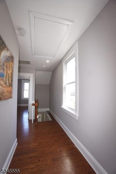 bonus room with wood finished floors, attic access, baseboards, and lofted ceiling