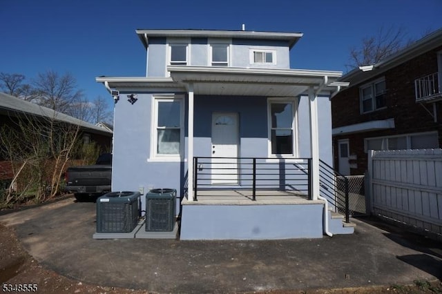 view of front of home featuring a porch, stucco siding, central AC, and fence