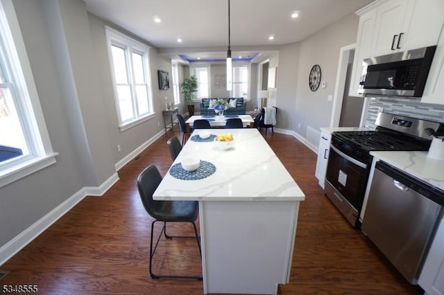 kitchen with tasteful backsplash, a kitchen breakfast bar, a center island, white cabinetry, and stainless steel appliances