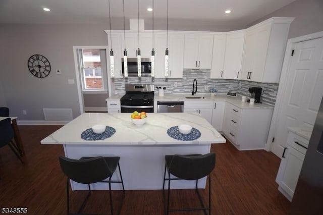 kitchen featuring a center island, a sink, a kitchen breakfast bar, stainless steel appliances, and dark wood-type flooring