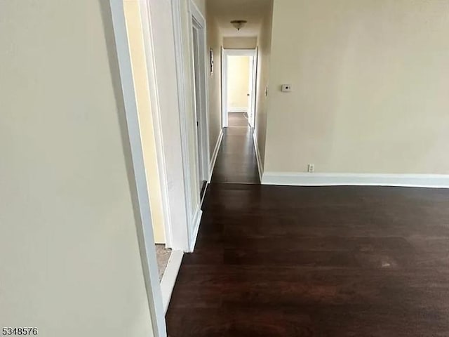 hallway with baseboards and dark wood-style flooring