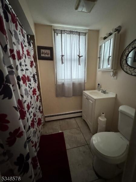 bathroom featuring baseboard heating, vanity, toilet, tile patterned flooring, and a shower with shower curtain