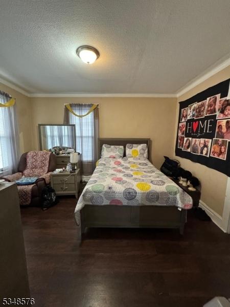 bedroom featuring wood finished floors, a textured ceiling, and crown molding