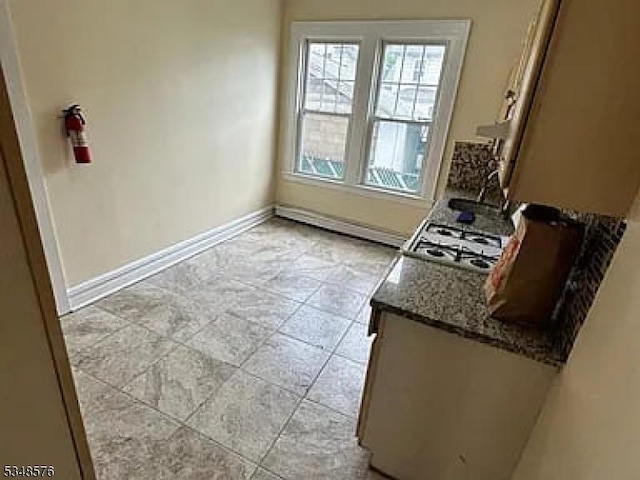 kitchen featuring stone countertops, baseboards, stainless steel gas cooktop, and a sink