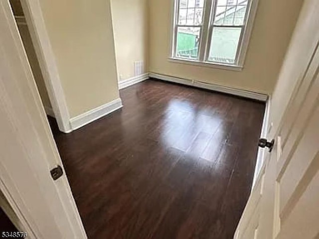 unfurnished room with baseboards and dark wood-style floors