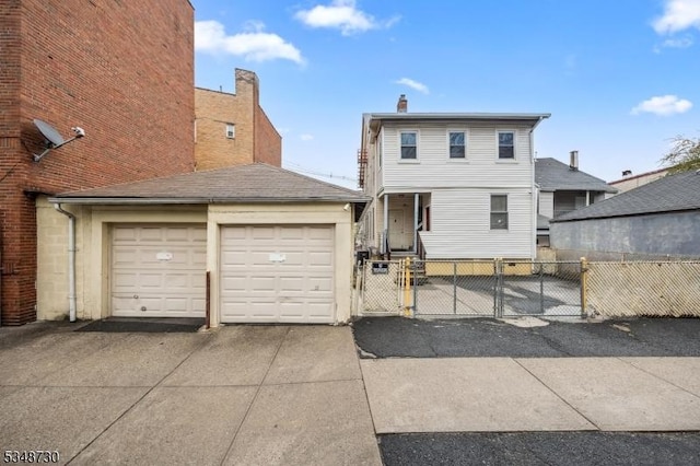 back of house with aphalt driveway, a garage, fence, and a gate