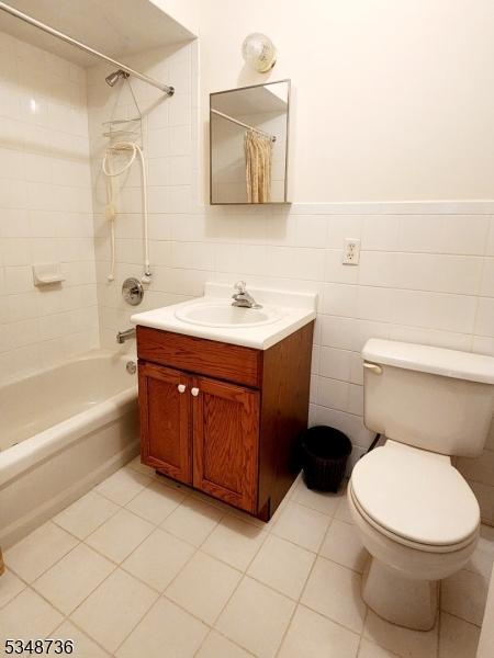 full bath with vanity, shower / tub combo with curtain, tile walls, toilet, and tile patterned flooring