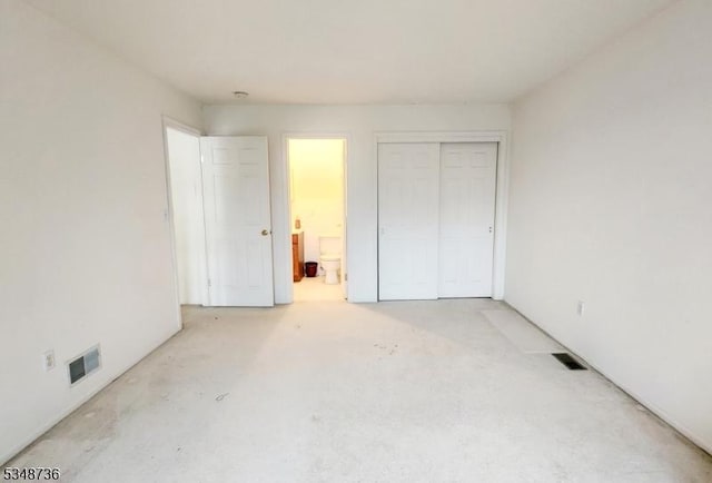 unfurnished bedroom featuring ensuite bath, visible vents, and a closet