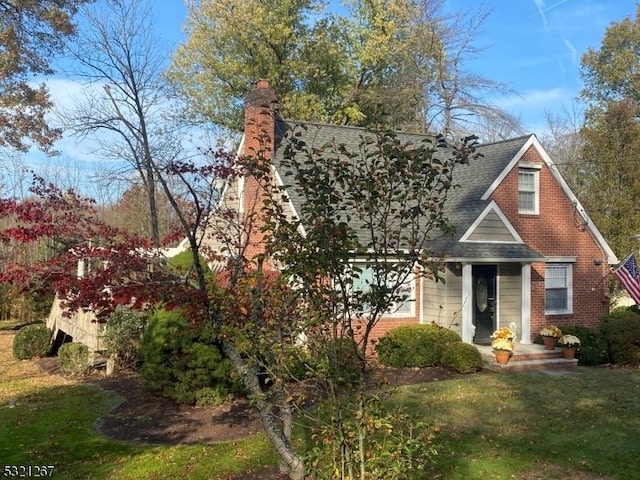 view of front of home with a front yard, a shingled roof, and a chimney