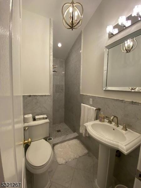 bathroom featuring vaulted ceiling, a chandelier, toilet, a shower stall, and tile walls