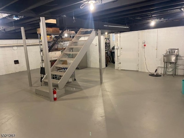 unfinished basement featuring stairway and concrete block wall