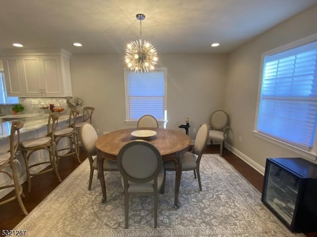 dining room with baseboards, recessed lighting, an inviting chandelier, and wood finished floors