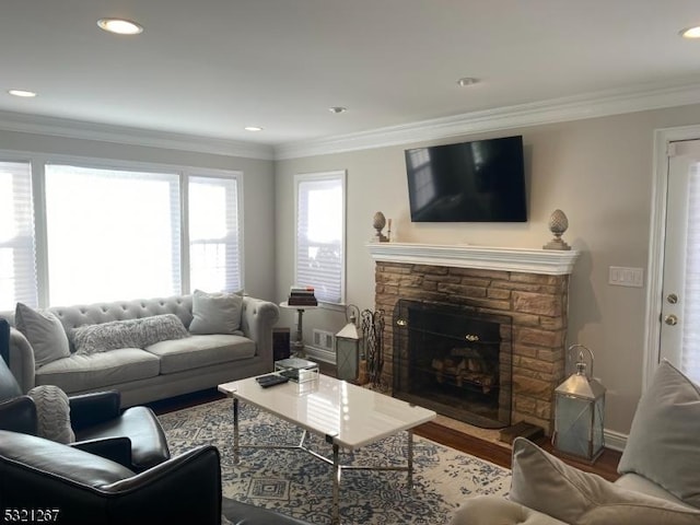living area featuring crown molding, visible vents, a stone fireplace, wood finished floors, and baseboards
