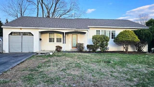 single story home featuring a garage, a front yard, brick siding, and driveway