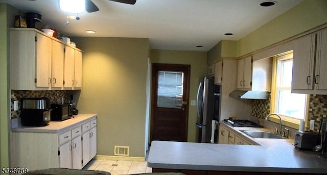 kitchen featuring freestanding refrigerator, visible vents, light countertops, a sink, and backsplash
