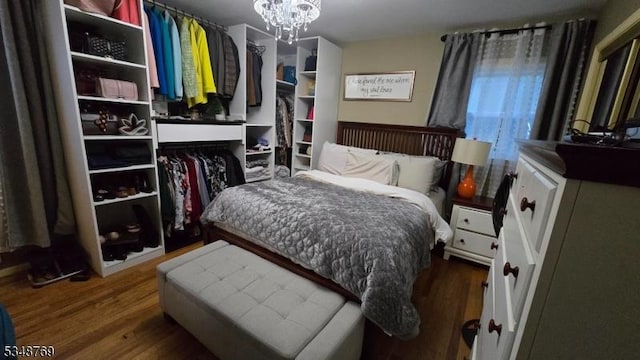 bedroom with wood finished floors and an inviting chandelier