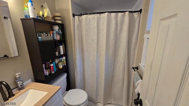 bathroom featuring toilet, curtained shower, and vanity