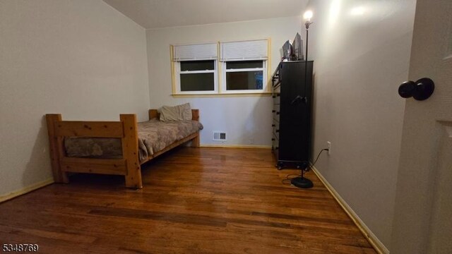 bedroom with visible vents, baseboards, and wood finished floors