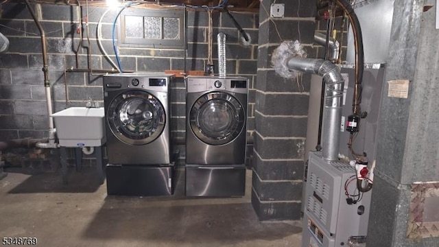 laundry area featuring a sink, heating unit, washing machine and dryer, and laundry area