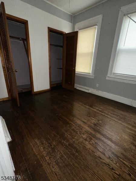 237 Warren St, Paterson City, NJ 07524 - unfurnished bedroom with dark wood finished floors, two closets, and multiple windows