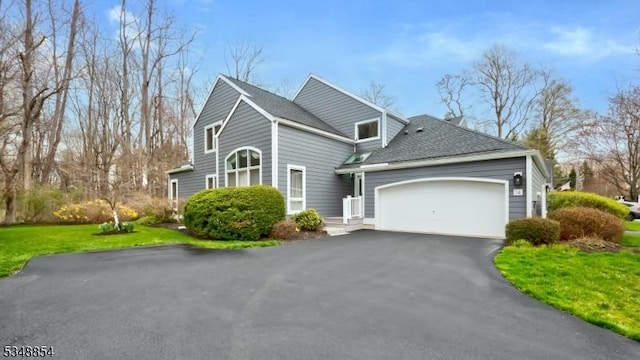 view of front of property featuring an attached garage, aphalt driveway, roof with shingles, and a front lawn