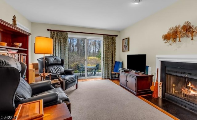 living area with a fireplace with flush hearth and wood finished floors