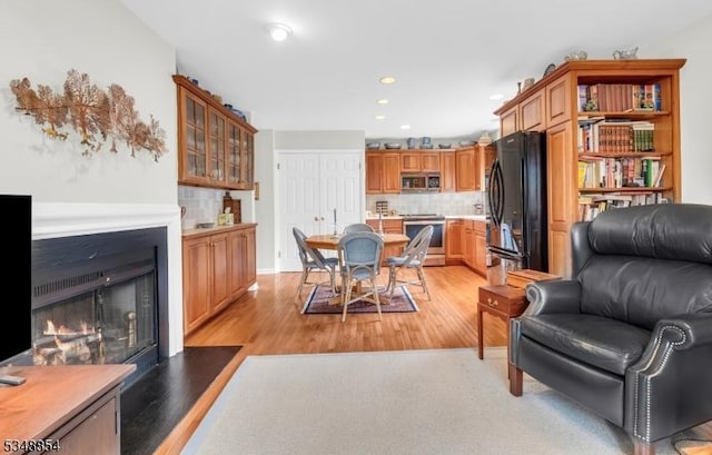 living area featuring light wood finished floors, recessed lighting, and a lit fireplace