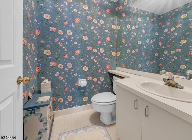 half bath featuring wallpapered walls, tile patterned floors, toilet, vanity, and baseboards