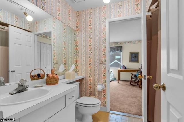 bathroom with tile patterned flooring, wallpapered walls, toilet, and vanity
