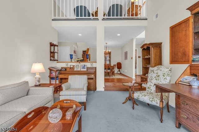 living area featuring a chandelier, carpet floors, a high ceiling, and visible vents