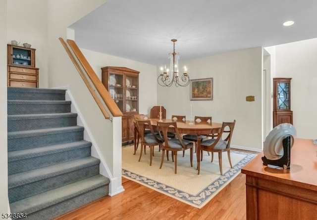 dining space featuring baseboards, recessed lighting, an inviting chandelier, light wood-style floors, and stairway